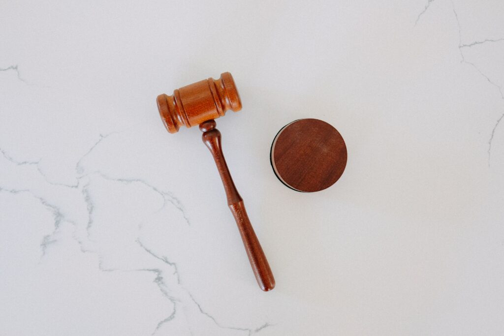 a gavel and block lie on a white marble background. They represent the law.