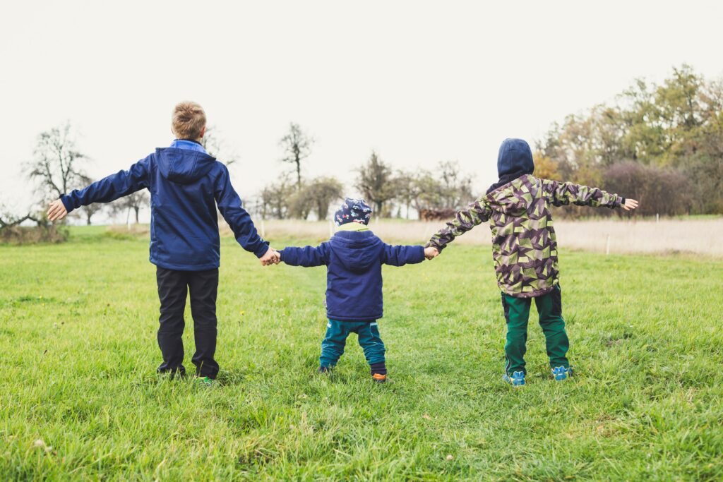 Three children hold hands in a field